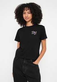 T-shirt preta de algodão com mangas curtas e gola redonda, com um design floral bordado em roxo e amarelo no peito.