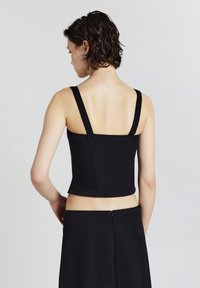 Schwarzes, kurzes Oberteil mit breiten Trägern, figurbetontem Design, glatter Textur und einem dezenten Reißverschluss auf der Rückseite. Schlichte und elegante Silhouette.