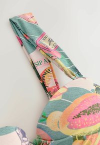 Ziedu raksta auduma soma ar mīkstu tekstūru; krāsas ir zaļa, rozā un dzeltena. Iezīme ir izturīga, plaša siksna ērtai nēsāšanai.