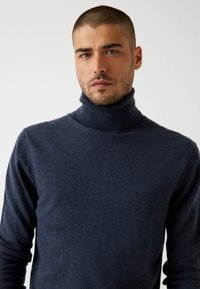 Marineblauer Rollkragensweater aus weichem Stoff, mit taillierter Passform, langen Ärmeln und geripptem Kragen, mit einer durchgehend glatten Textur.