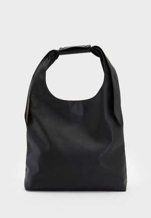 Musta nahkainen hobo-laukku, jossa on yksi pehmeä, pyöreä kahva; ominaisuuksina sileä pinta ja minimalistinen muotoilu. Ei näkyvää metalliosaa tai koristeita.