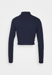 Marinblå ribbade långärmade crop top med hög krage och åtsittande midja. Slät textur, enkelt design, inga synliga detaljer eller utsmyckningar.