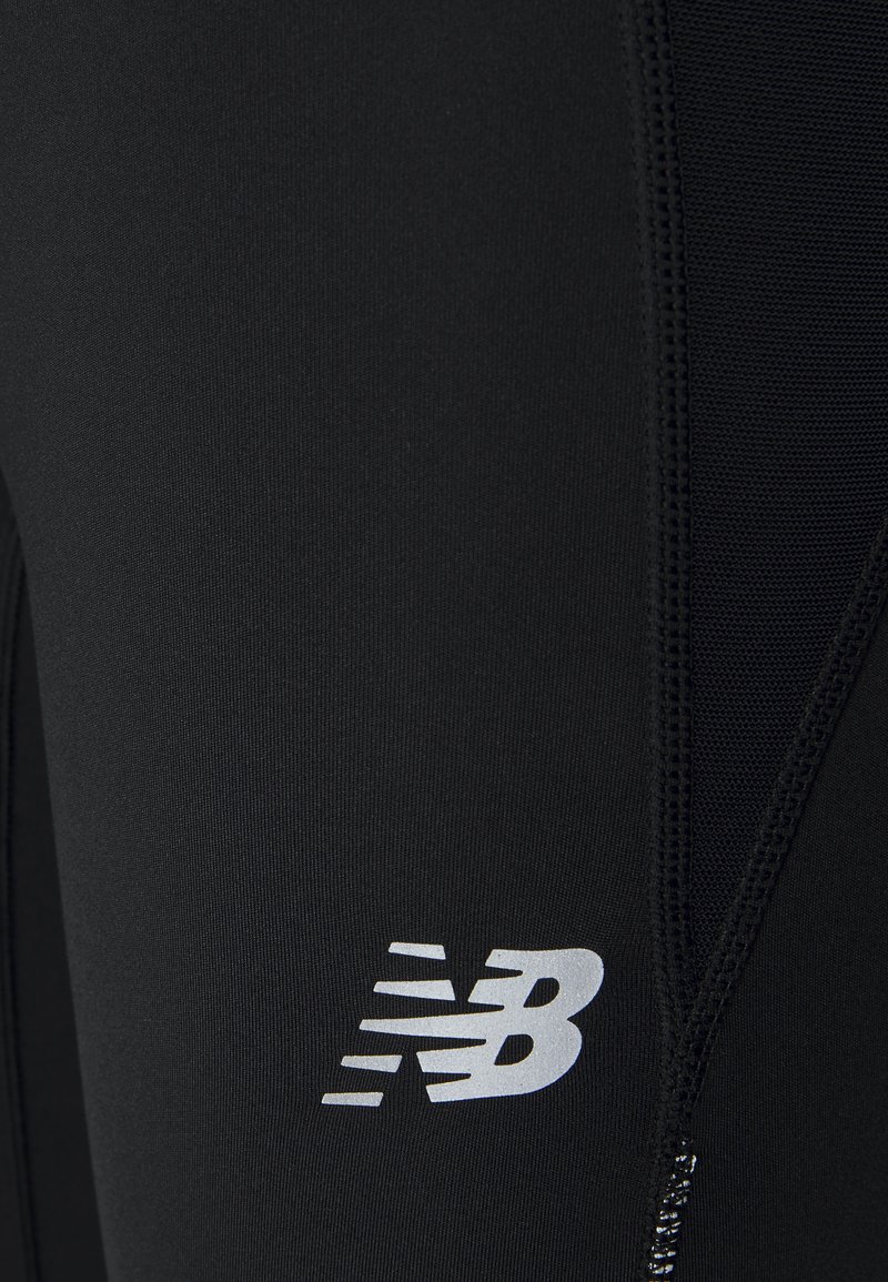 Leggings de sport noirs avec un design épuré, en matériau synthétique, et panneaux latéraux texturés. Comprend un logo réfléchissant "New Balance".