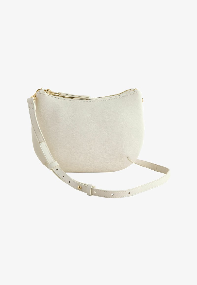 Sac bandoulière en cuir blanc à forme courbe, fermeture zippée sur le dessus, et une sangle détachable et ajustable. Détails en métal doré.