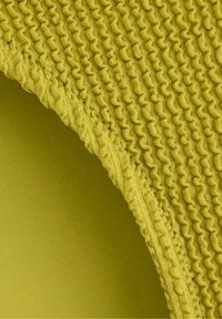 Texturerad tyg i livlig gul färg med rynkade detaljer och en slät, solid baksida i en ljusare nyans av gult.