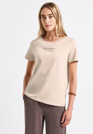Beige T-shirt met korte mouwen en ronde hals; voorzien van een geprinte "awesome" tekstontwerp. Zacht katoenmateriaal, ontspannen pasvorm, gecombineerd met donkergrijze broek.