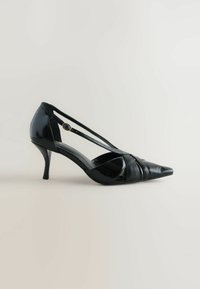 Black patent leather high heel shoe with pointed toe, crisscross strap design, and a small decorative button accent on the side.