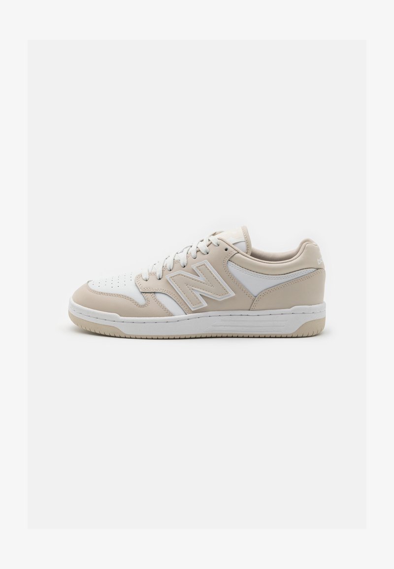 Beżowe i białe sneakersy wykonane z materiałów skórzanych i syntetycznych, z perforowanym noskiem, wyściełanym kołnierzem i białymi sznurówkami.