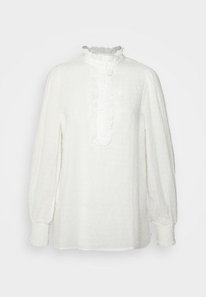 Biała bluzka z teksturowanym, kropkowanym wzorem, falbaną przy dekolcie i guziczkach oraz elastycznymi mankietami na rękawach balonowych.