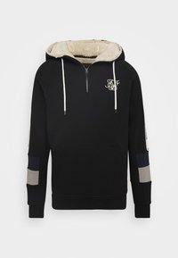 Felpa nera con colletto zip, foderata in sherpa beige, con lacci di colore crema e logo ricamato; presenta accenti bicolore sulle maniche.