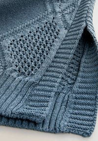 Țesătură albastră tricotată, cu un amestec de modele texturate, inclusiv modele nervurate și cu țesătură deschisă, având un aspect moale, dar structurat.