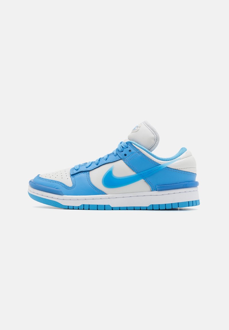 Tenisky Nike Dunk Low s bílým a světle modrým koženým svrškem, modrými akcenty, perforovanou špičkou a texturovanou gumovou podrážkou.