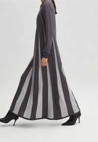 Lange gestreepte jurk met afwisselend donkergrijze en lichtgrijze panelen, lange mouwen, een hoge halslijn en een vloeiende uitstraling.