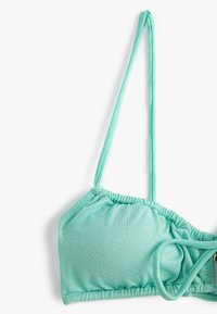 Hellgrüner Bikini-Oberteil mit verstellbaren Trägern, geraffter Textur und glatter Oberfläche. Verfügt über einen Hakenverschluss für einen sicheren Sitz.