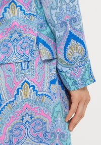 Bluză cu mâneci lungi, decorată cu modele intricate de paisley în nuanțe de albastru, roz și auriu. Material moale, cu o textură netedă și manșete cu nasturi.