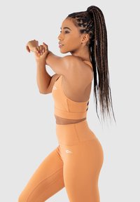 Orange atletisk crop top och högmidjade leggings. Slät, elastisk tyg med en åtsittande design. Logotypdetalj på leggings.