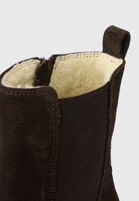 Καφέ μποτάκι αστραγάλου από σουέντ και υφαντό ύφασμα με μαλακό, χνουδωτό εσωτερικό και μικρή θηλιά στο πάνω μέρος για εύκολη εφαρμογή.