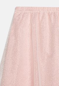 Jupe en tulle rose avec une ceinture élastique, ornée de petites paillettes dorées qui créent un effet scintillant sur tout le tissu.