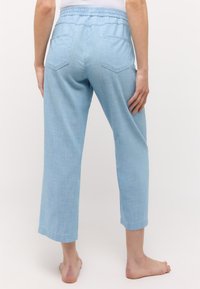 Helle blaue, taillierte Hosen aus weichem, strukturiertem Stoff. Mit einem elastischen Bund, zwei Gesäßtaschen und einem geraden Beinanschnitt.