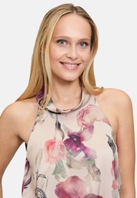 Bloemen mouwloze top met een zachte, gedrapeerde halslijn. De stof is licht met een pastel achtergrond en meerkleurige bloemenpatronen.