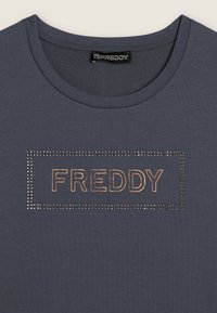 T-shirt grigio scuro con scollatura rotonda, caratterizzata da un logo metallico "FREDDY" contornato da strass in forma rettangolare.