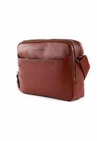 Borsa a tracolla in pelle marrone con una texture liscia, scomparti con zip e una tracolla. Presenta una tasca frontale e dettagli del logo.