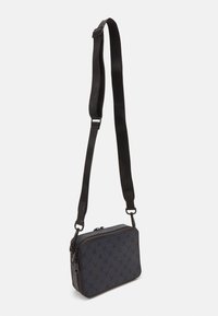 Schwarze rechteckige Schultertasche aus gemustertem Stoff, verstellbarem Tragegurt, Reißverschlussverschluss und dezenten Hardware-Details.