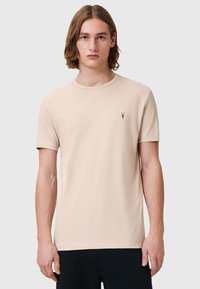 T-shirt in cotone beige con collo rotondo, maniche corte e un piccolo logo ricamato sul lato sinistro del petto. Tessuto liscio, vestibilità comoda.