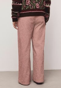 Pantaloni cu picior larg, în model de carouri roșii și albe. Țesătură moale, texturată, cu croială lejeră, tiv vizibil și fără accesorii notabile.