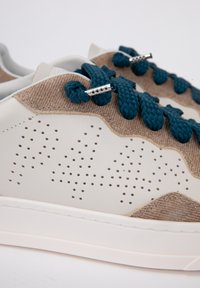 Sneaker con corpo in pelle liscia color crema, dettagli in corduroy marrone, particolari perforati e lacci intrecciati verde scuro con hardware argentato.