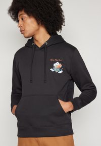 Fekete pamut kapucnis pulóver, kenguruzsebbel, húzózsinóros kapucnival, és hímzett grafika felhőkkel és szöveggel a mellkason.