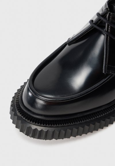 Schwarze Lederschuhe mit glänzender Oberfläche und strukturierter schwarzer Gummisohle. Verfügen über eine runde Zehenform und Schnürdesign.