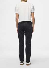 Beskuren vit t-shirt kombinerad med högmidjade, rakbenade svarta jeans. Utstyrseln har en minimalistisk design med en klassisk passform.