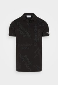 Svart kortärmad polo med spridd "Calvin Klein Jeans" text i olika storlekar och orienteringar, med krage och två knappar.