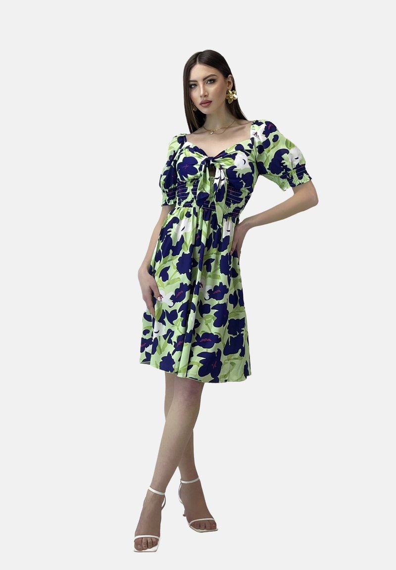 Vestido floral que presenta una combinación de colores verde, marino y blanco. Mangas cortas abullonadas, escote con cordón y una silueta fluida.