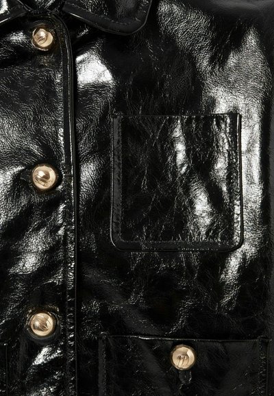 Giacca nera lucida con colletto classico, bottoni a pressione dorati e taschino sul petto, dal texture liscia e leggeri segni di piega.