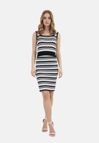 Rochie cu un model în dungi zig-zag în alb și negru, cu o formă ajustată și un decolteu rotund. Are bretele groase și un design până la genunchi.