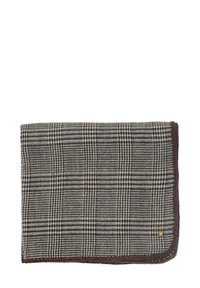 Bufanda de lana a cuadros en tonos negro y crema, con un borde cosido en marrón y un pequeño logo de acento dorado en la esquina.