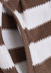 Brązowo-białe paskowane tkaniny o teksturowanym splocie, z naprzemiennymi grubymi i cienkimi paskami oraz lekko postrzępionymi brzegami.