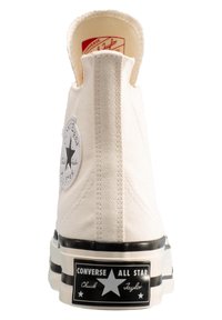 Vit canvas hög-topp sneakers med svart gummisulor, stjärnlogotyp patch och svart accentrand på hälen. Har strukturerad tyg.