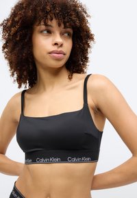Μαύρο bralette από λεία υφάσματα με ρυθμιζόμενους ιμάντες και φαρδιά ελαστική ταινία με το λογότυπο "Calvin Klein" στο τελείωμα.