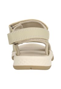 Beige Sandale mit zwei Stoffriemen und einem strukturierten Fußbett. Die Sohle ist weiß mit einem geometrischen Muster. Verstellbare Schnalle für den richtigen Sitz.