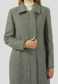 Abrigo de jacquard en grises y blancos con cuello de solapa, mangas largas y corte recto, con cierre de botones y bolsillos laterales.