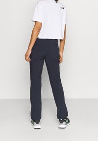 Navy outdoor broek met een rechte snit en elastische tailleband, gemaakt van lichte stof. Gecombineerd met een cropped wit T-shirt.