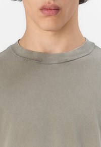 Grå bomull T-skjorte med rund hals, med en glatt tekstur og subtilt blanding av toner, synlige sømmer rundt kragen.