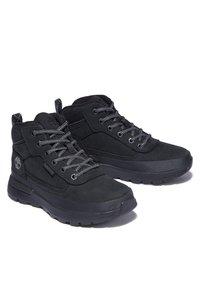 Chaussures montantes noires en suède texturé et panneaux en maille, avec des lacets gris, une semelle en caoutchouc et un accent de logo sur le côté.