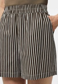 Bruna och vita randiga shorts med elastisk midja och sidofickor, med en mjuk textur och rak skärning till fållens nederkant.