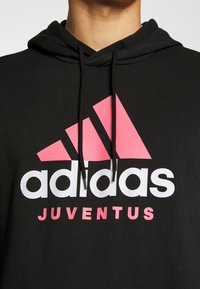 Felpa nera con cappuccio, con logo Adidas rosa e bianco e la scritta "JUVENTUS" in rosa, cappuccio con cordino e texture di tessuto morbido.