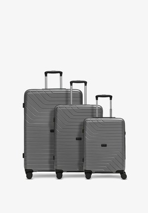 Tres maletas duras grises con mangos telescópicos y cuatro ruedas, organizadas por tamaño de grande a pequeña.