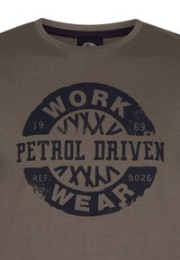 Oliwkowa bawełniana koszulka z okrągłym dekoltem i dużym, granatowym nadrukiem tekstowym: "WORK PETROL DRIVEN WEAR," z efektami postarzania.